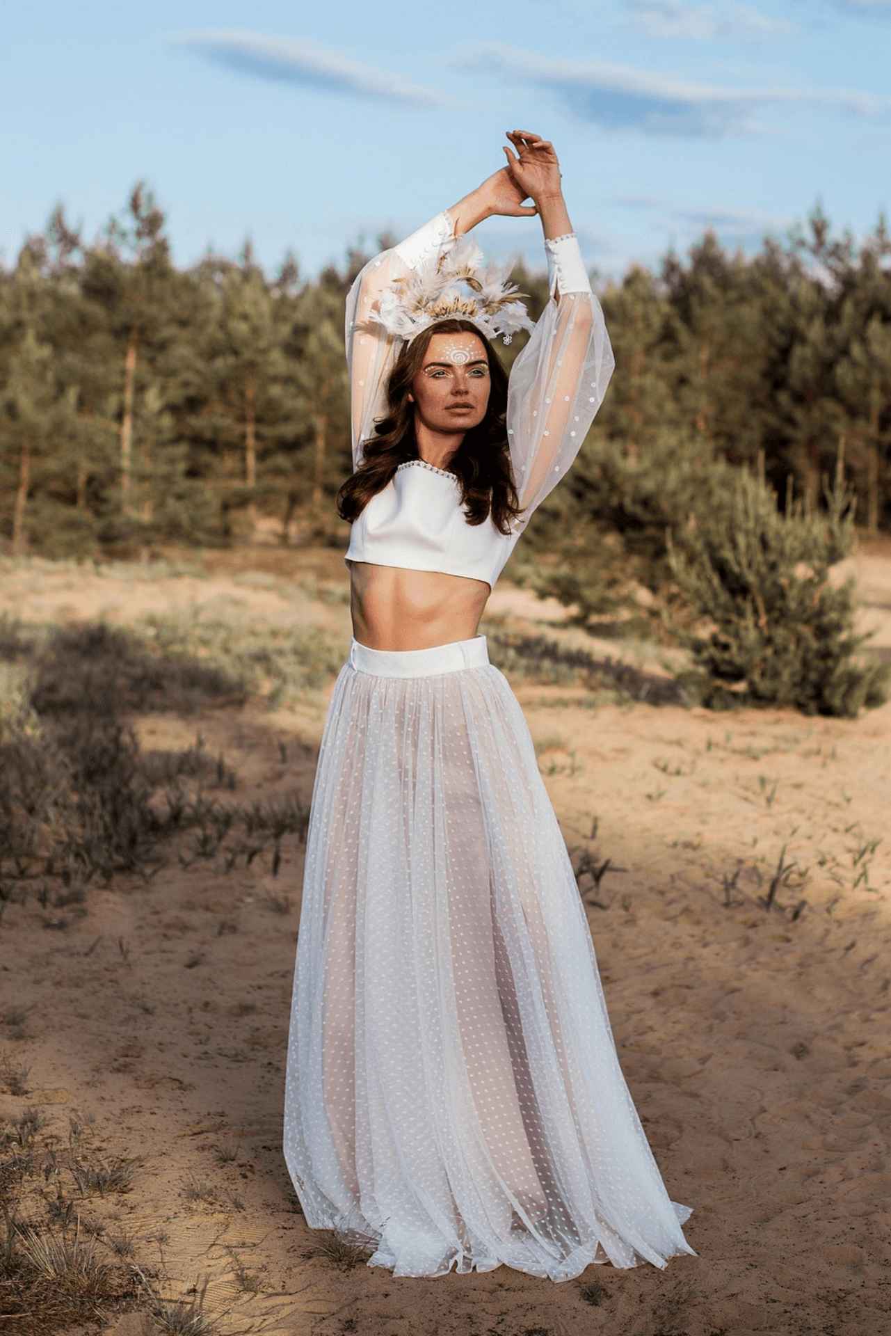 Woman wearing a sheer white maxi skirt and crop top with long transparent sleeves – ethereal fashion trend for spring 2025.