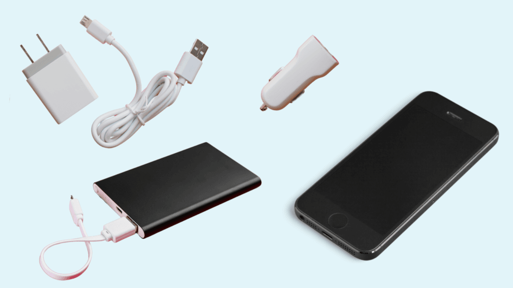 Flatlay of travel tech essentials including a power bank, phone, wall charger, USB cable, and car adapter – must-have mobile charging accessories.