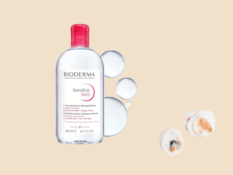 Bioderma Sensibio H2O micellar water with cotton pads and water drops on beige background