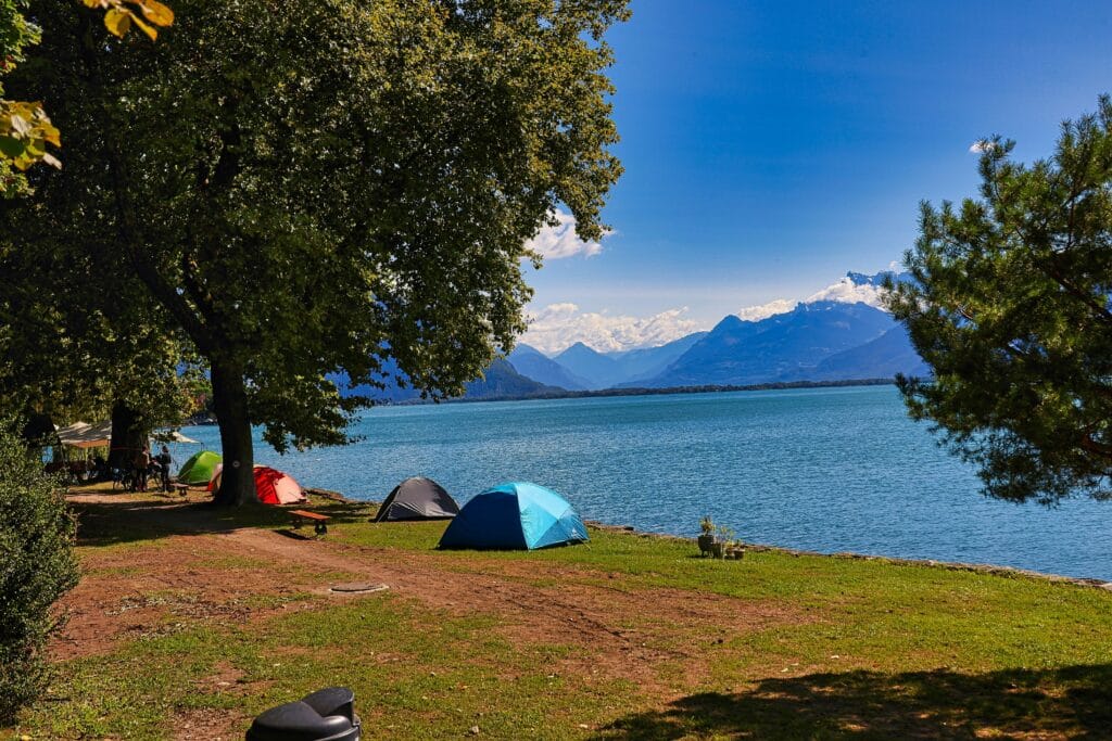 Clean and peaceful lakeside camping spot with colorful tents and mountain view in the background
