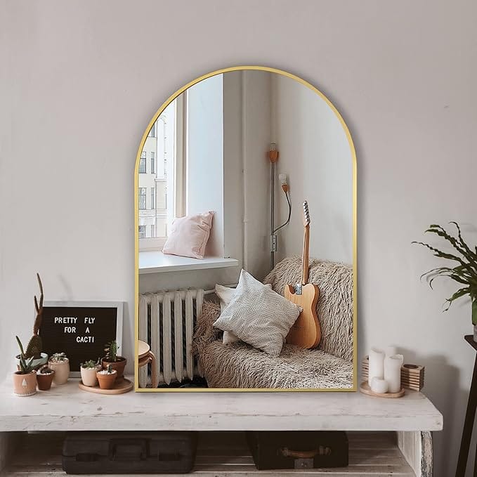 arched gold wall mirror reflecting cozy pastel nook – feminine home decor inspiration