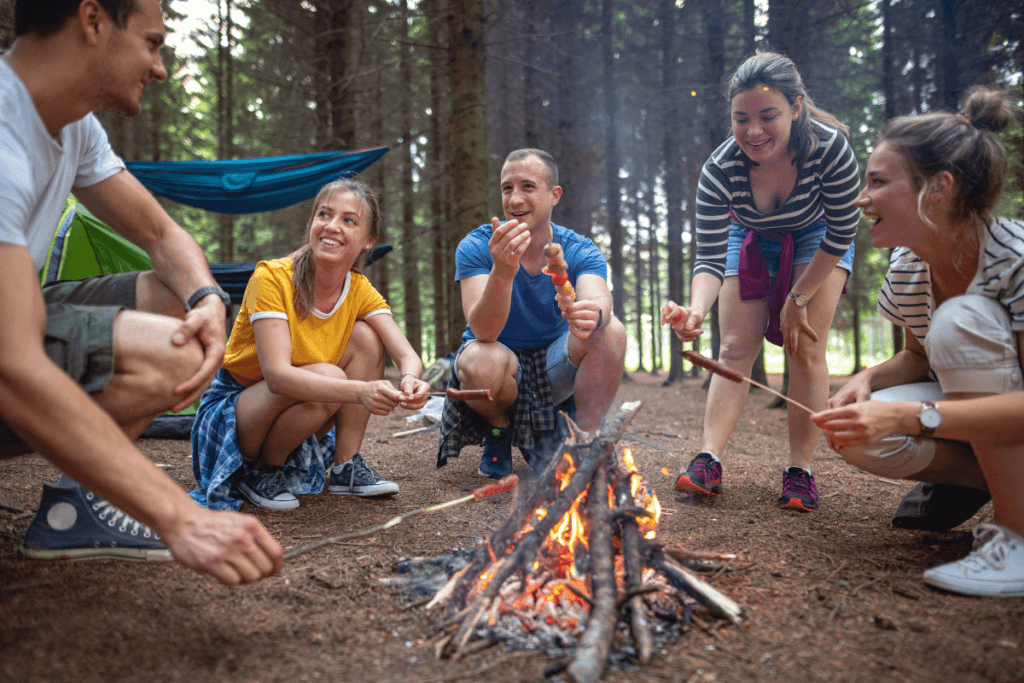 Group of friends enjoying a campfire in the forest during a camping trip