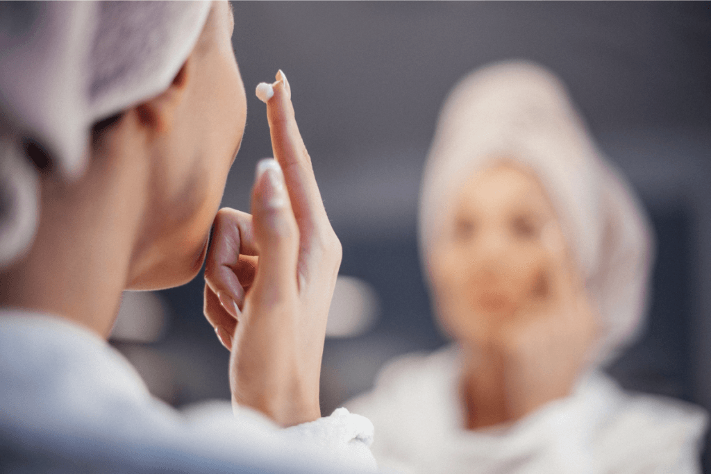Woman applying face cream in front of a mirror, enjoying a quiet self-care ritual