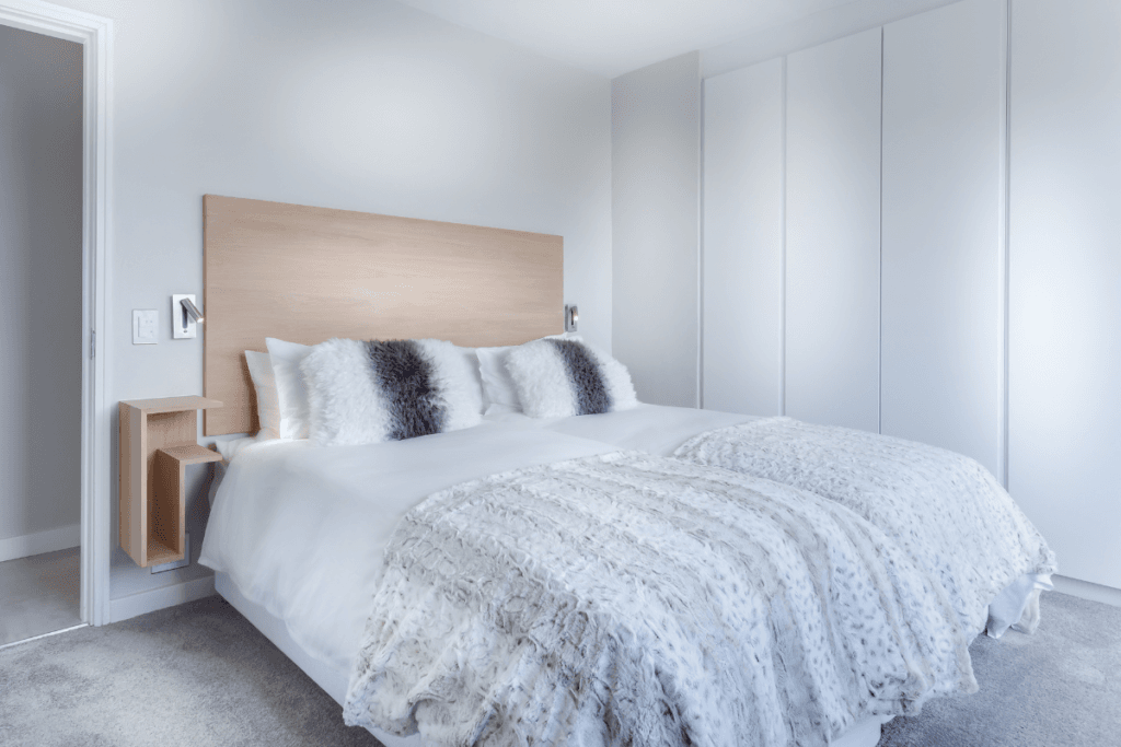 white bedroom with faux fur pillows and blanket – cozy feminine textures for home decor