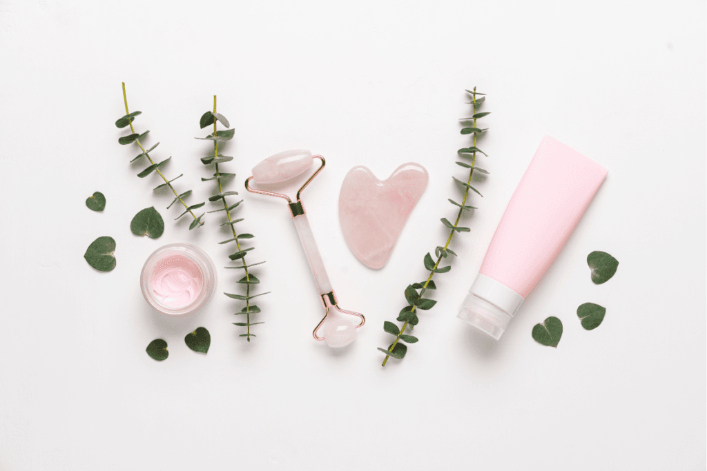 Flat lay of skincare products with jade roller, pink moisturizer, and eucalyptus – a calming beauty ritual