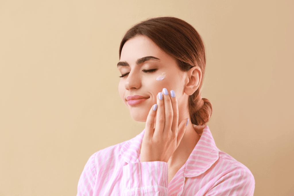 Woman with eyes closed gently applying moisturizer, reflecting on her beauty self-care journey