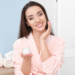 Smiling woman in pink robe applying skincare cream as part of her morning beauty self-care routine