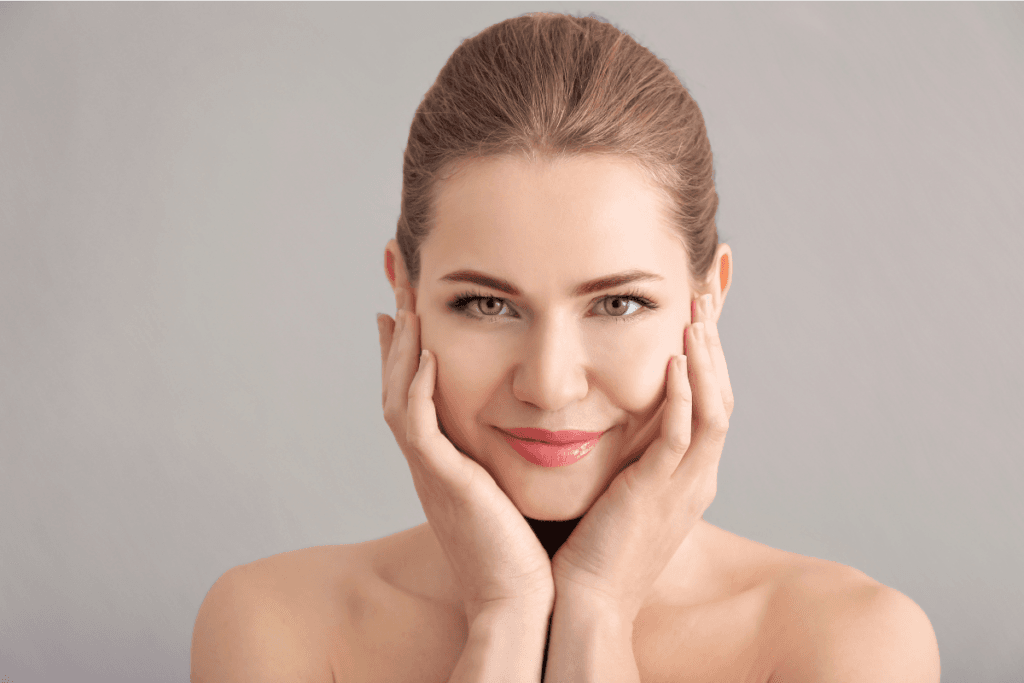 Smiling woman gently holding her face after a calming beauty self-care routine