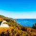 Tent set up on a scenic coastal cliff with panoramic ocean view under a clear blue sky