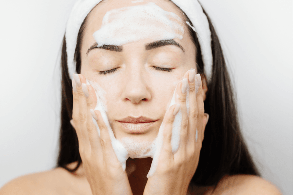 Woman gently massaging foaming cleanser onto her face with eyes closed – step-by-step skincare routine