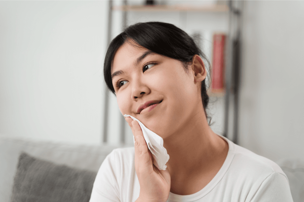 Smiling woman gently wiping her face with a cleansing wipe – light and easy skincare routine