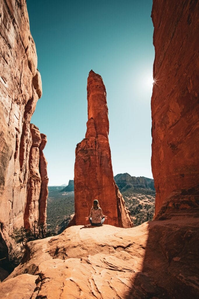Woman meditating on Cathedral Rock Trail, surrounded by Sedona’s red rock formations