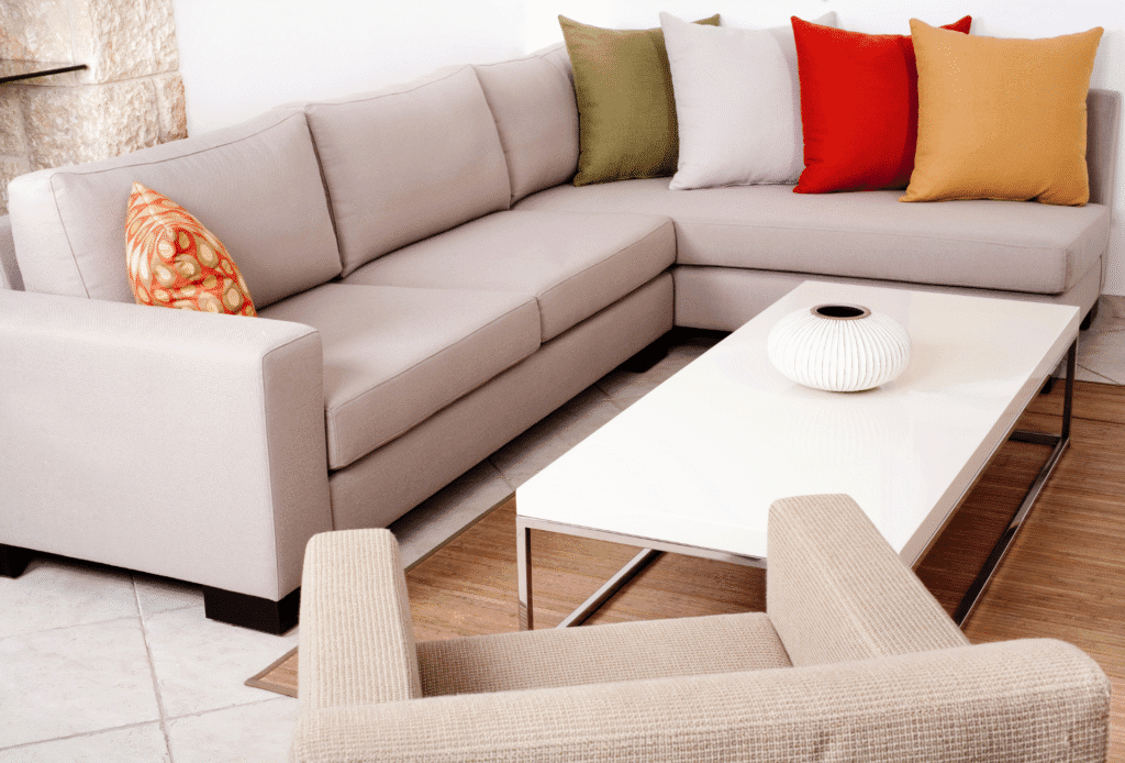 Colorful throw pillows on a neutral sectional sofa with a modern white coffee table in a cozy living room