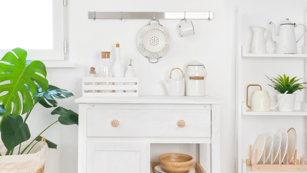 White kitchen corner with Scandinavian decor, natural wood accessories, and potted plant – minimalist home styling on a budget