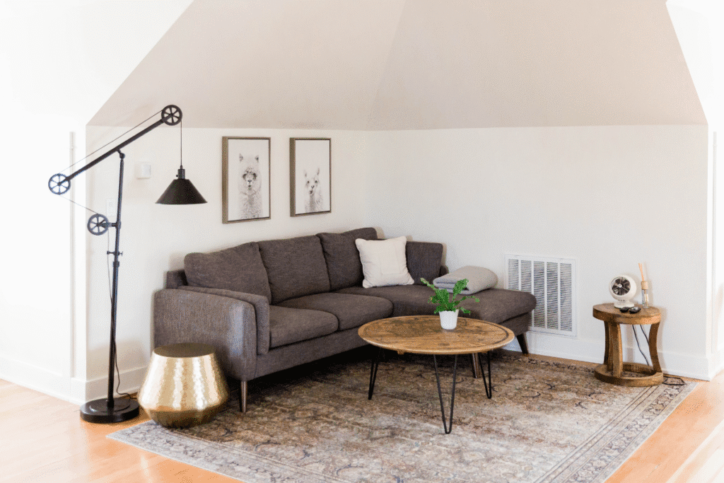 Neutral-toned living room with a minimalist wall art set above a dark gray sofa, a round coffee table, and eclectic modern lighting